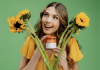 Functional Mushrooms and the HPA Axis: A Clinically Aligned Model for Non-Stimulant Cognitive Support and Longevity in Healthcare Woman smiling and holding a jar of Genius Joy supplement with sunflowers in front of her against a green backdrop.